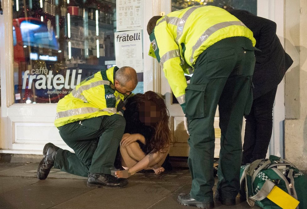Zdravotníci se starají o opilou dívku v Londýně.