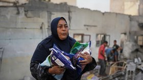 Palestinská žena odnáší pytle cukru, jediné věci, které se jí podařilo zachránit z domu zničeného při nočním izraelském útoku v Nusajrátu v centrální části Pásma Gazy (23. 10. 2026)