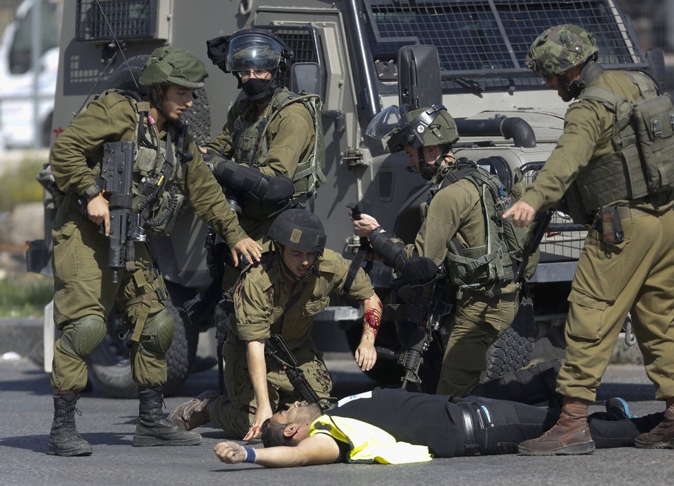 Izraelští vojáci se sklání nad pobodaným kolegou.