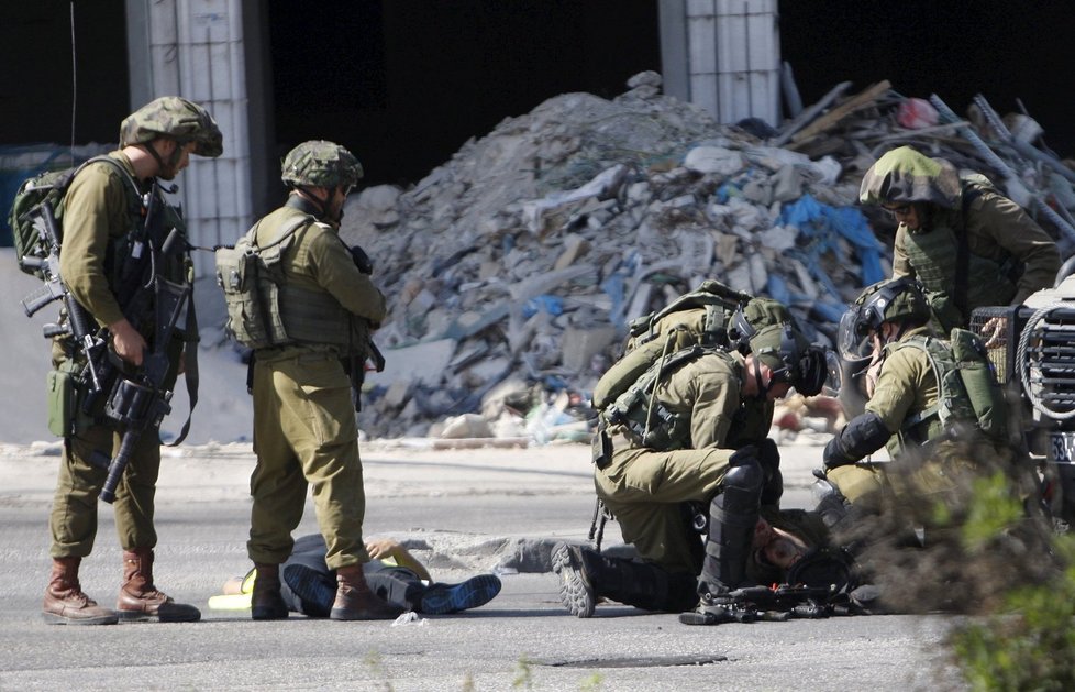 Izraelští vojáci se sklání nad pobodaným kolegou a mrtvým útočníkem.