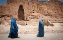 Místní ženy oblečené podle přísných pravidel islámského náboženství procházejí kolem zničené památky