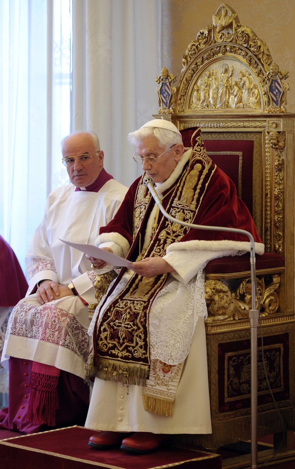 Mons. Franco Comaldo přihlíží, jak papež Benedikt XVI. oznamuje svou rezignaci.