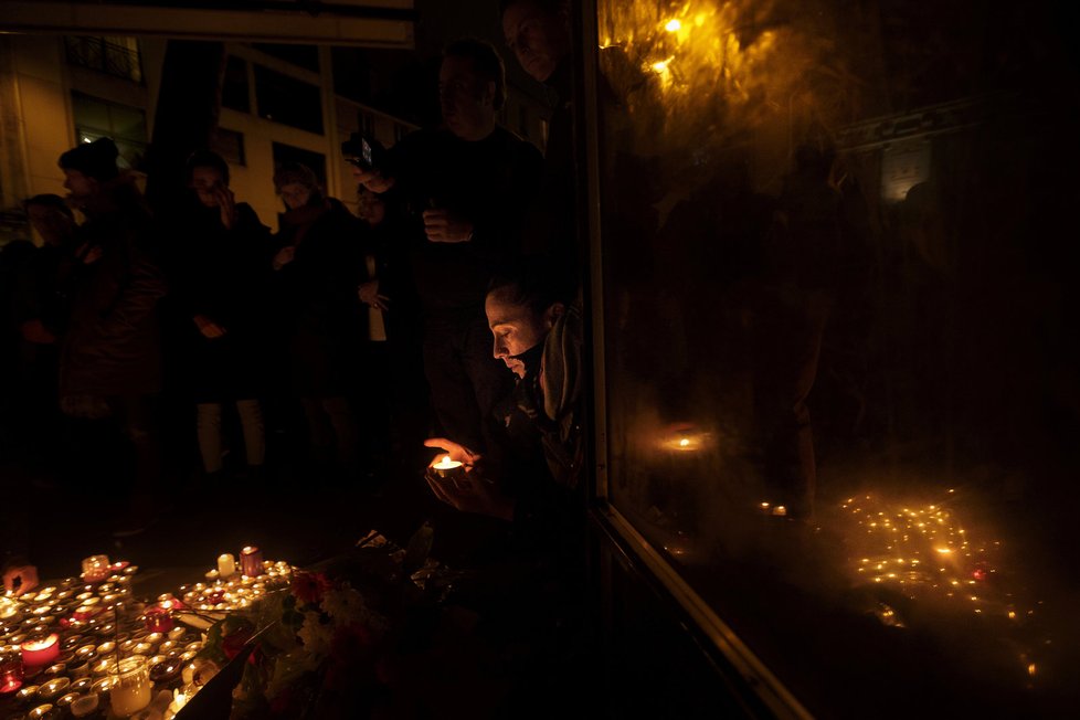 Žena zapaluje svíčku před restaurací Belle Equipe v Paříži na počest těch, kteří během teroristických útoků 13. 11. zemřeli.
