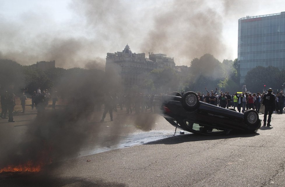 Bouřlivé demonstrace řidičů taxíků ve Francii: Jedno z aut protestující převrátili.