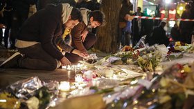 Lidé poblíž klubu Bataclan pokládají květiny a svíčky jako uctění obětí teroristických útoků 13. 11.