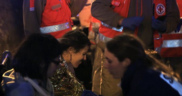 Evakuovaní lidé jsou ošetřováni a uklidňováni po útocích v klubu Bataclan v Paříži, 13. 11. 2015.