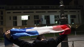 Muž s francouzskou vlajkou před ambasádou v Berlíně