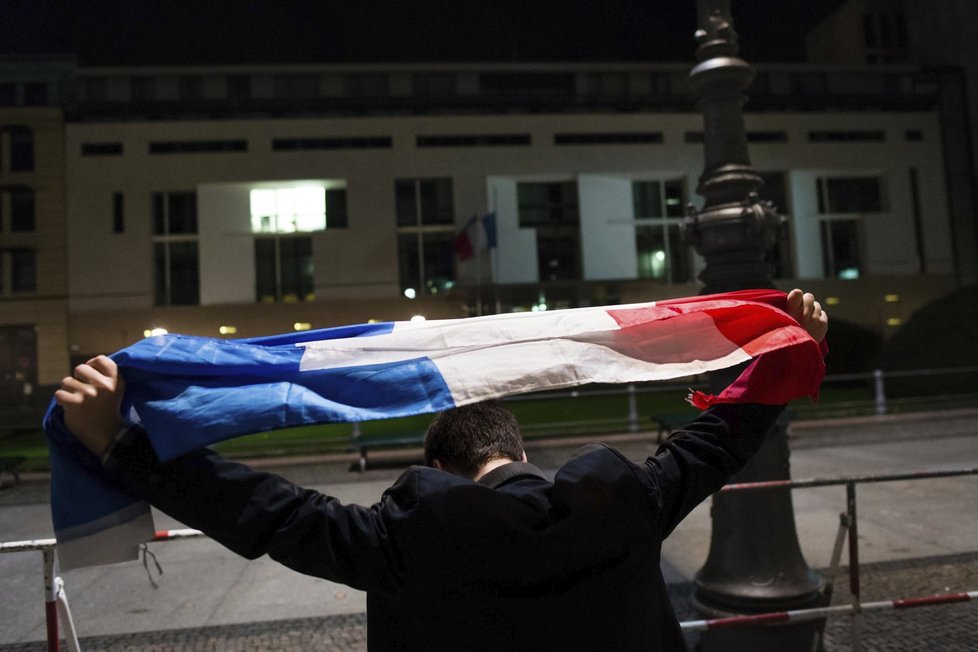 Muž s francouzskou vlajkou před ambasádou v Berlíně