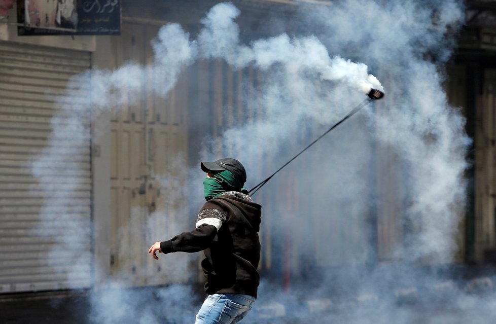 Palestinský protestující hází po izraelských vojácích granát se slzným plynem, který Izraelci vystřelili na demonstranty.