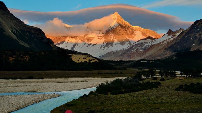 Vycházející slunce vrhá jasné červánky na východní stěnu Cerro San Lorenzo, se 3706 metry druhou nejvyšší horu Patagonie. Andy, táhnoucí se v délce více než 1500 kilometrů, oblast doslova rozřízly na dva naprosto odlišné typy krajiny: Na západ od horských hřbetů se rozkládají deštné pralesy Chile, čím dál k jihu, tím četněji se do souše zakusují fjordy Tichého oceánu. Východním směrem od And, v dešťovém stínu mohutného horstva, zbylo dost místa na rozlehlé pláně patagonské stepi