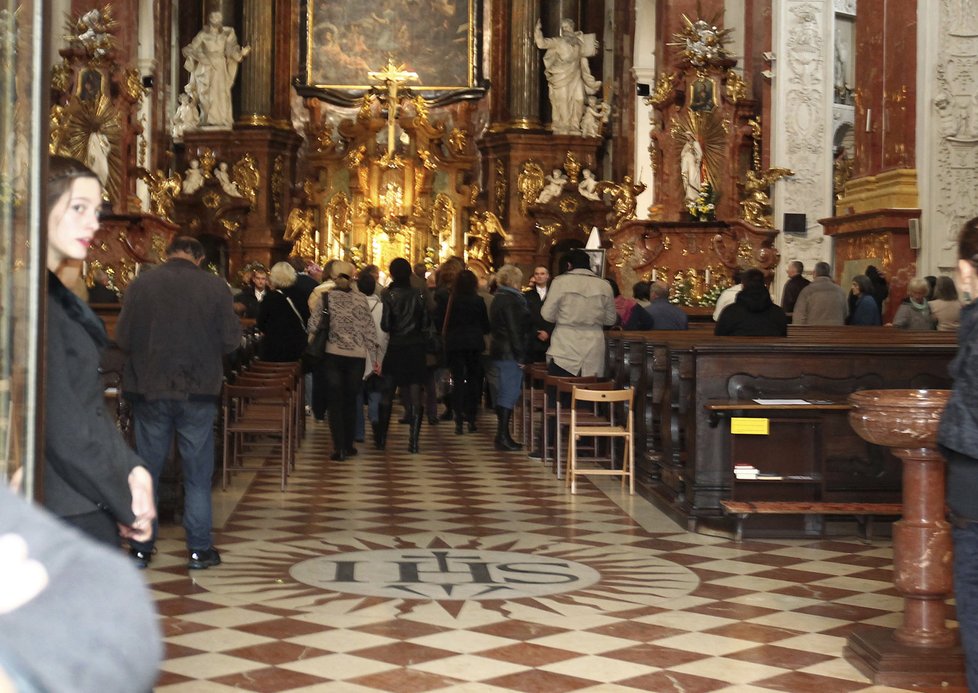 Kostel se pomalu naplňuje lidmi, kteří přišli položit kytice k rakvi zemřelého herce.