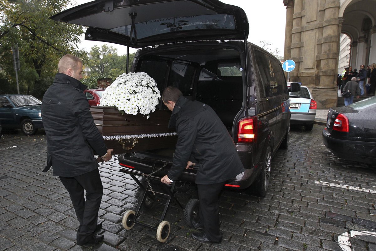 Ke kostelu přijelo pohřební auto s rakví.