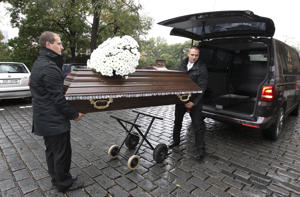 Ke kostelu přijelo pohřební auto s rakví.