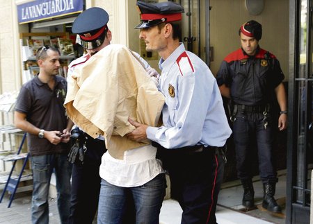 Španělská policie odvádí ženu ze stanice, kde se k otřesnému činu doznala.