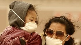 Lidé v Pekingu si museli kvůli písku zakrývat obličeje rouškami.
