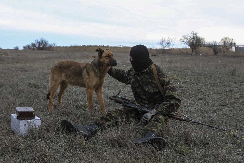 Ukrajinský voják si hraje se psem během hlídky poblíž vesnice Strelkovo