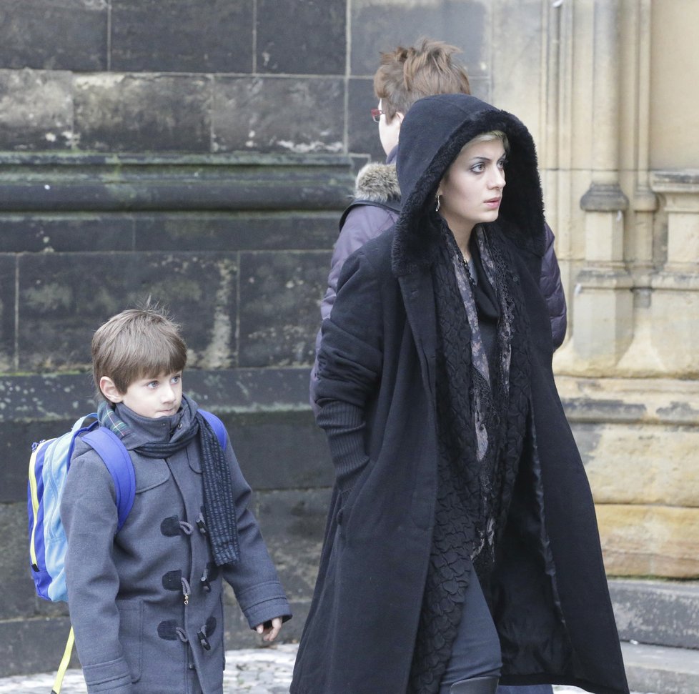 Tajemná žena v kapuci odchází se svým malým synkem.