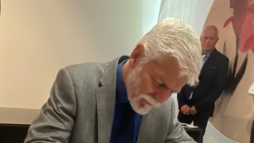 Petr Pavel se zapisuje do pamětní knihy. Na památku v porcelánce Thun dostal kočku.