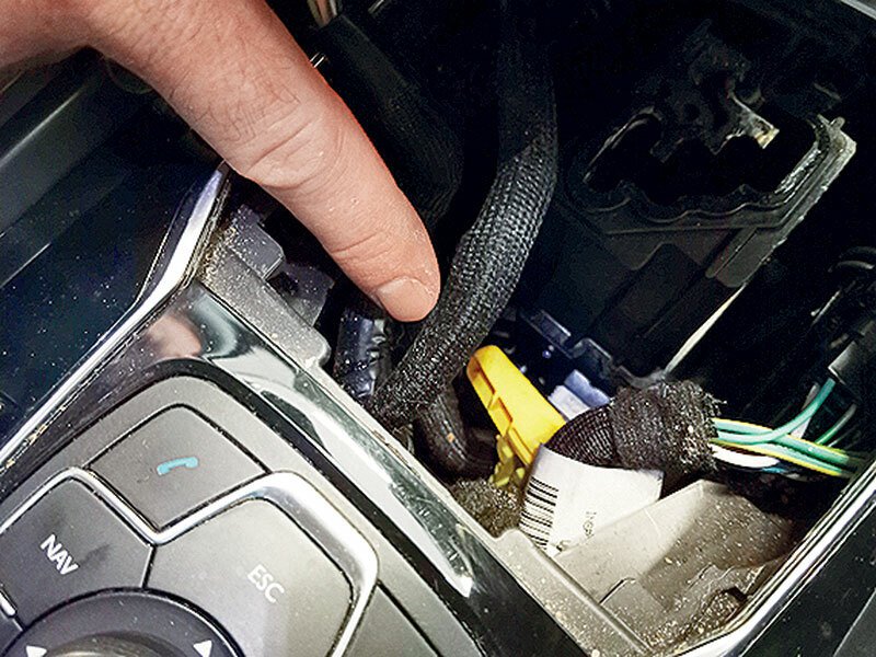 Verze s automatem mají vždy elektrickou parkovací brzdu. Kdyby náhodou klekla nebo jste potřebovali odbrzdit vůz s vybitou baterií, lze ji mechanicky odjistit tímto žlutým kolíkem schovaným v prostoru pod manžetou volicí páky.