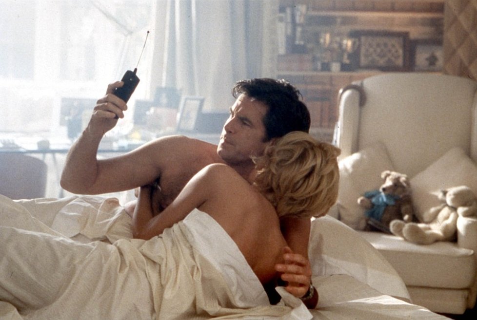 Když Bond nesleduje hodinky, tak kontroluje čas aspoň na telefonu. Film Zítřek nikdy neumírá a Pierce Brosnan a Cecilia Thomsen.