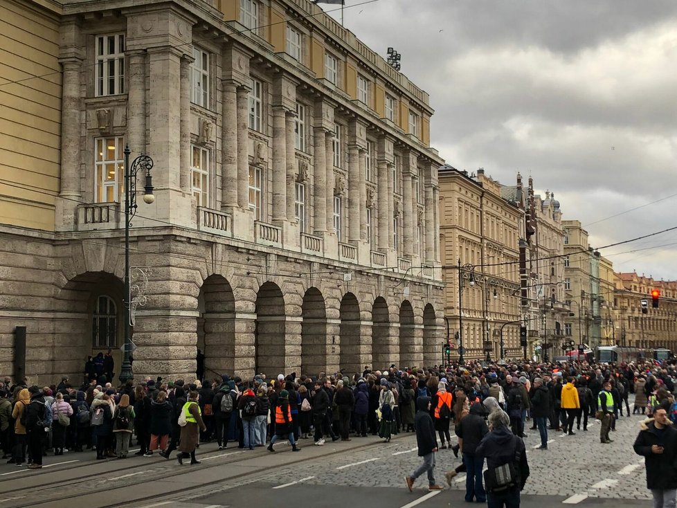 Pietní průvod za oběti střelby na FF UK. Účastníci piety symbolicky objímají budovu fakulty. V lidském řetězu je tolik lidí, že stojí hned v několika řadách. (4. leden 2024)