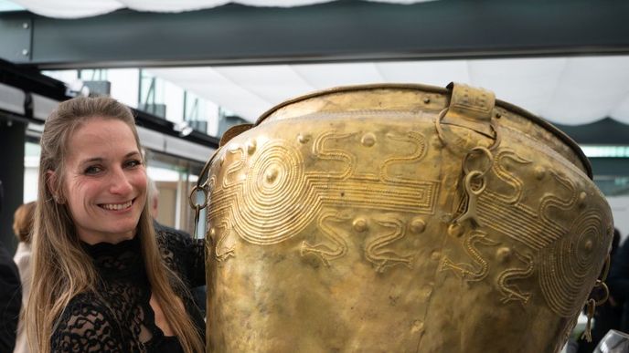 Bronzová kráska z Kladiny – nejstarší obětina piva ve střední Evropě bude vystavena 5. 10. 2026 – 31. 1. 2027 v Archäologisches Museum Frankfurt. Na snímku kopie vědra z Kladiny vytvořená P. Rajnochem a prezentovaná při přednášce archeoložkou T. Joškovou. Bronzová kráska z Kladiny – nejstarší obětina piva ve střední Evropě bude vystavena 5. 10. 2026 – 31. 1. 2027 v Archäologisches Museum Frankfurt. Na snímku kopie vědra z Kladiny vytvořená P. Rajnochem a prezentovaná při přednášce archeoložkou T. Joškovou.