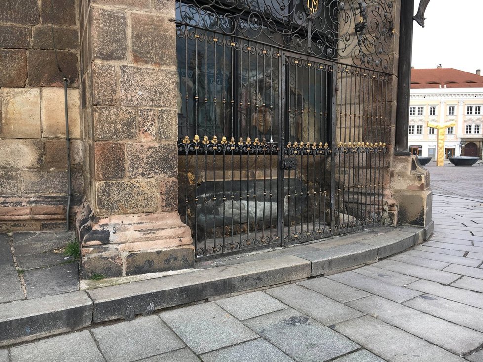 Kovová plastika rukou je na obrubníku katedrály sv. Bartoloměje u mříže s andílky.