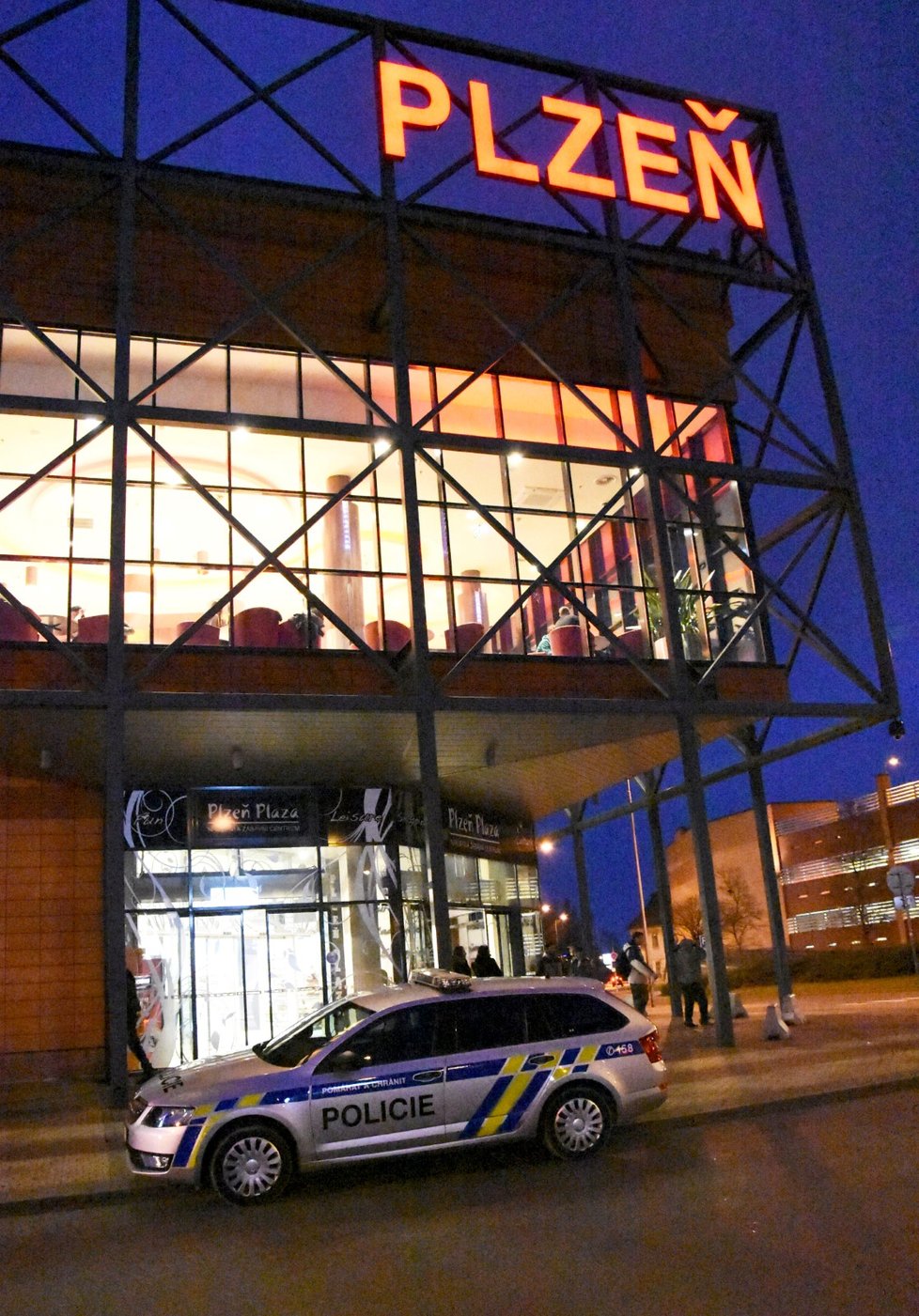 Policejní auto před vchodem do nákupního centra Plaza.