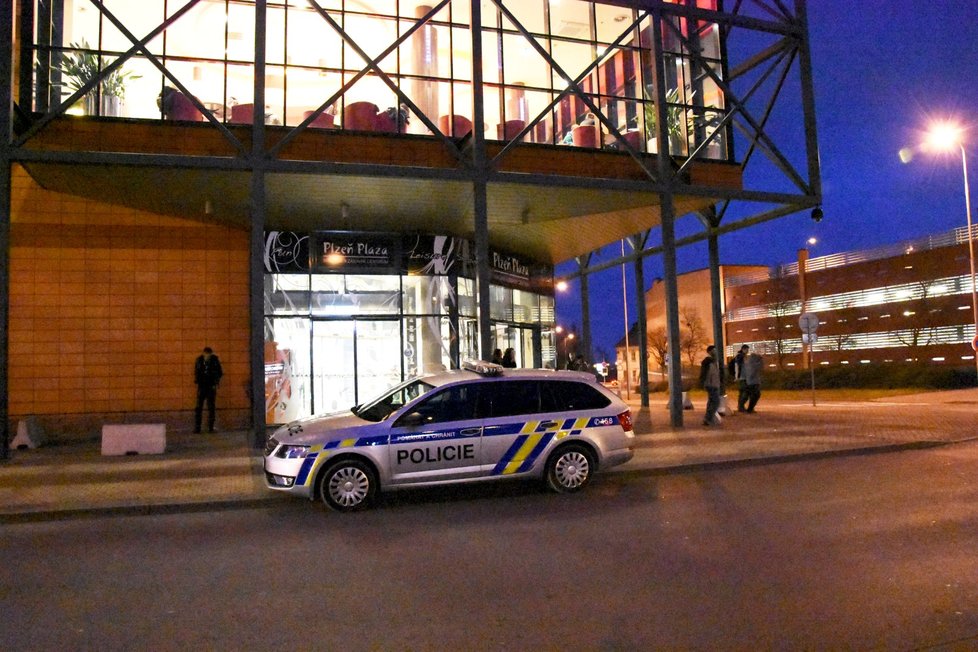 Policejní auto před vchodem do nákupního centra Plaza.