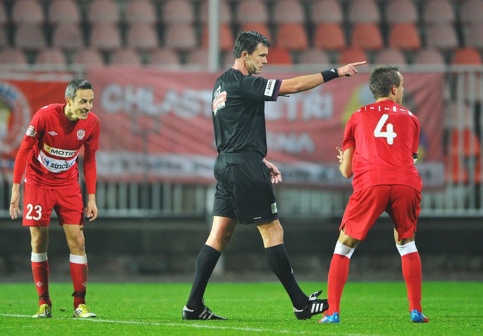 Sudí Franěk ukazuje na značku pokutového kopu, fotbalisté Brna marně protestují nebo se už jen smějí.