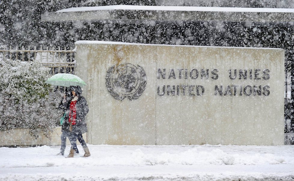 Chodci opatrně našlapují do sněhu před budovou OSN v Ženevě.