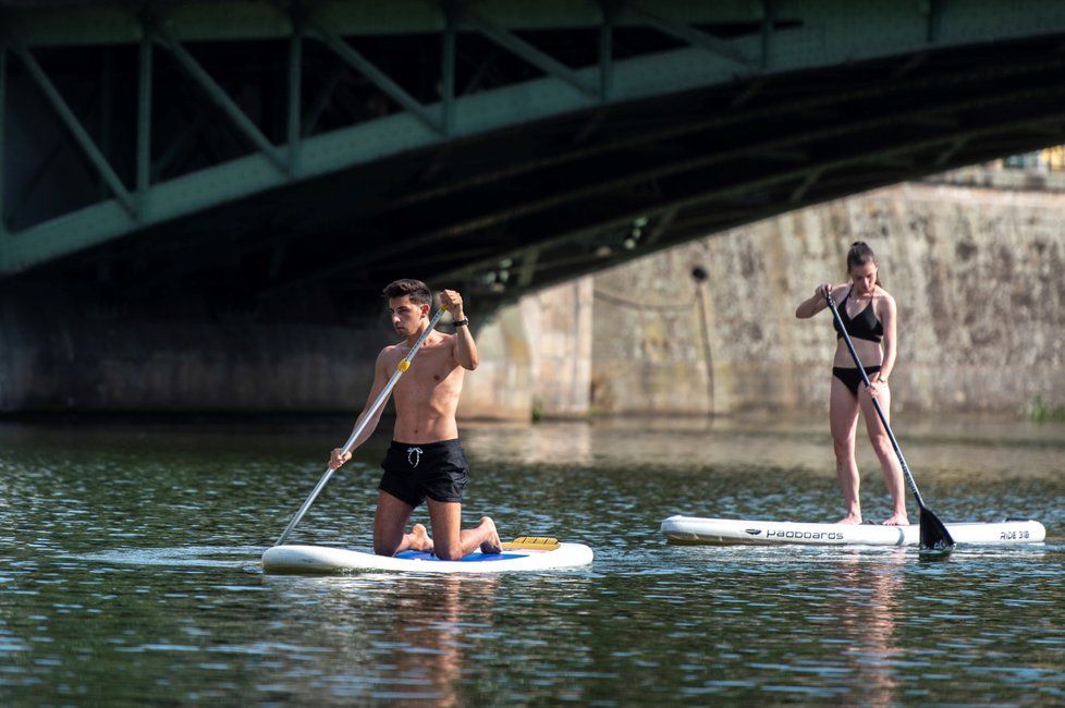 Vysoké teploty budou i na podzim lákat k osvěžení. Snímek z 3. srpna 2018 je z centra Hradce Králové, kde lidé plují po Labi na paddleboardech, koupou se v řece nebo se opalují na náplavkách.