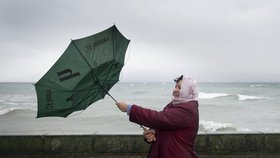 Žena se u Ženevského jezera marně snaží rozevřít deštník