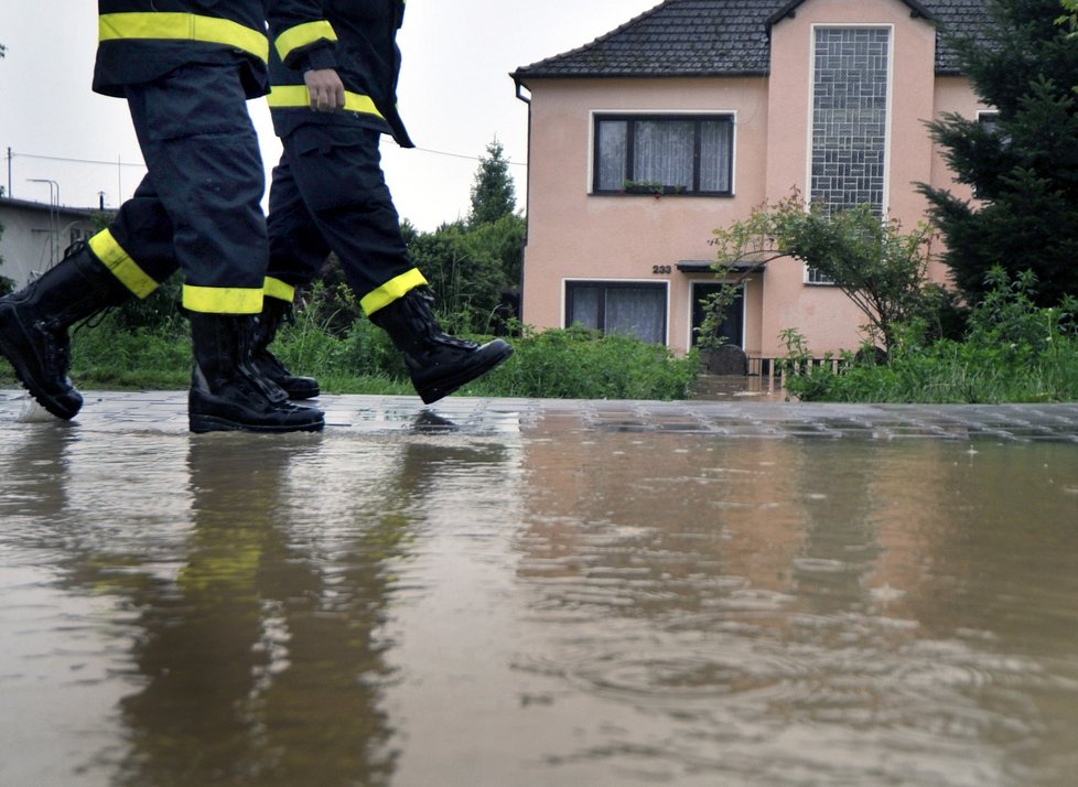 Dobrovolní hasiči pomáhali 18. května obyvatelům v zaplavených domech na hlavní ulici v Troubkách na Přerovsku.