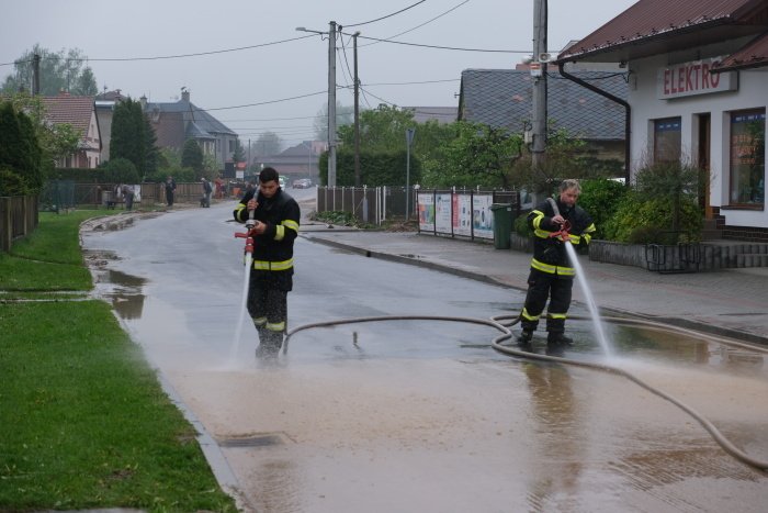 Hasiči odklízí po lijáku nánosy bahna v obci Hať v Moravskoslezském kraji.