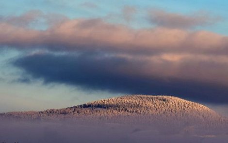Sluncem zalitý kopec Žalý u Vrchlabí, které zůstalo pod šedou pokličkou.