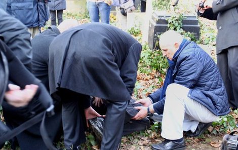 Přemysl Sobotka a Jiří Besser pomáhají zraněnému fotografovi, kterému spadl hrobní kámen na nohu.