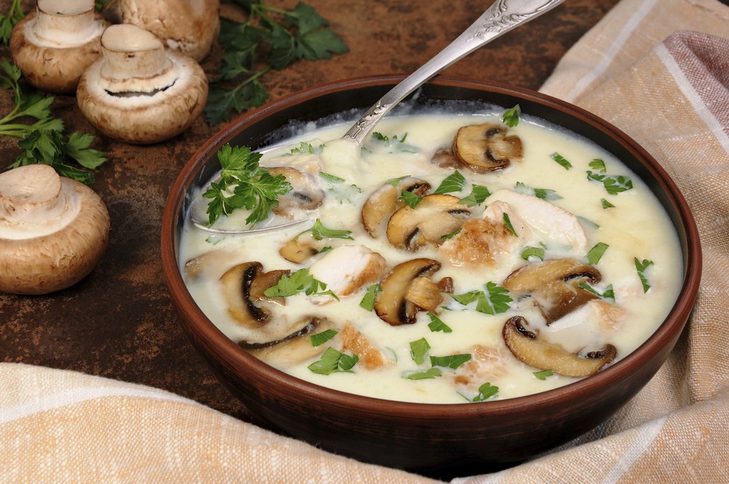 Krémovou žampiónovou polévku na talíři dozdobte plátky na másle osmažených hub.