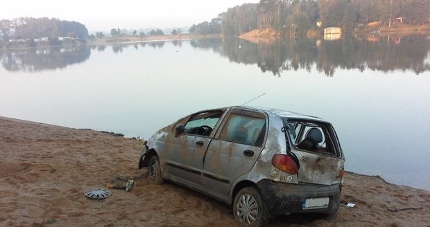 Automobil skončil po nehodě na střeše na břehu písníku