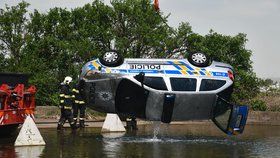 Policejní vůz sjel z neznámých příčin do jímky plné vody. Vytahovat jej museli hasiči.