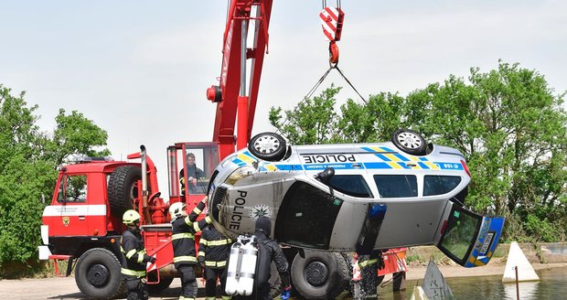 Policejní vůz sjel z neznámých příčin do jímky plné vody. Vytahovat jej museli hasiči.