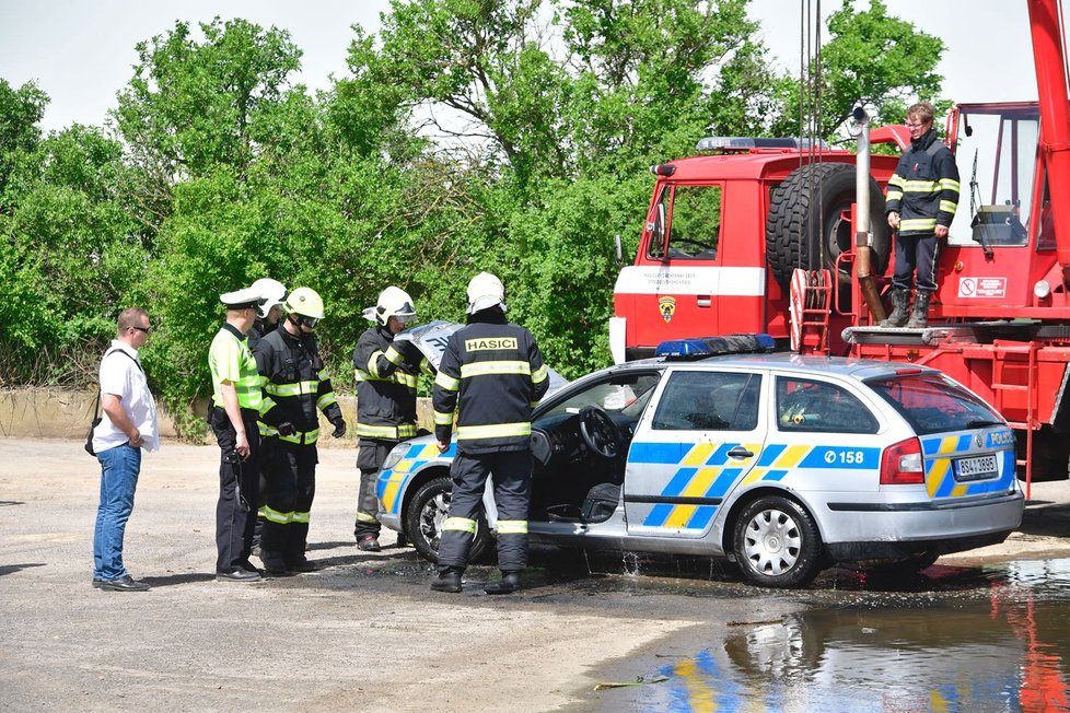 Policejní vůz sjel z neznámých příčin do jímky plné vody. Vytahovat jej museli hasiči.