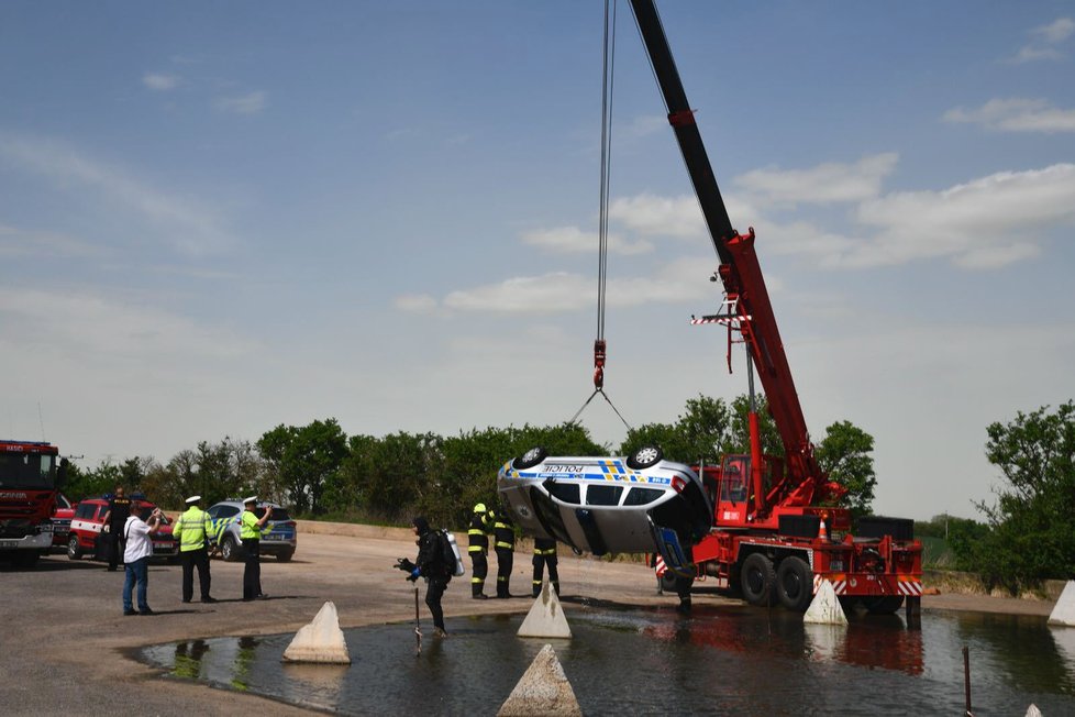 Policejní vůz sjel z neznámých příčin do jímky plné vody. Vytahovat jej museli hasiči.