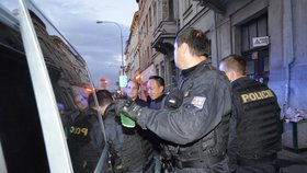 Policisté nakládají zatčeného Vietnamce do služebního auta a odvážejí k výslechu.