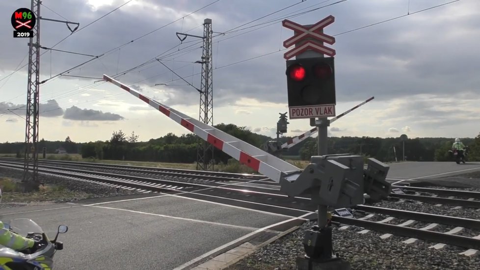 ...první policista mizí v zatáčce, u závor zastavuje jeho kolega...