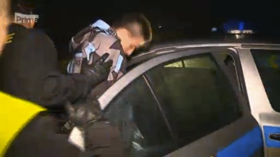 Policisté odvádí Josefa N. do policejního auta.