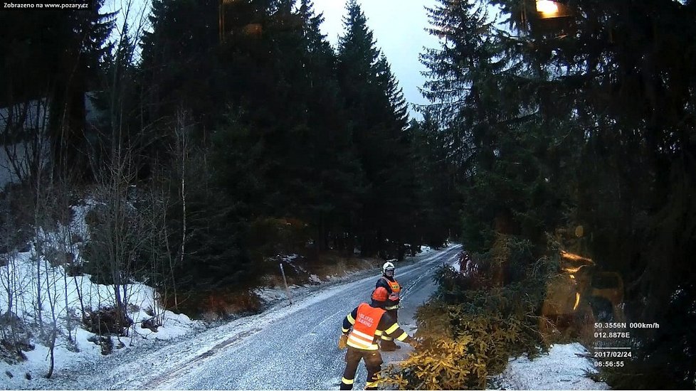 Hasiči varují řidiče, aby projížděli kolem stromů s větší opatrností, silný vítr je vyvrací na silnici.