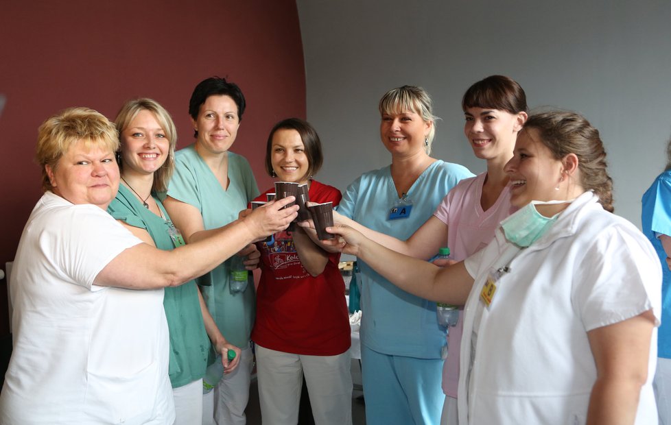Lékaři si ťukají kelímky s kávou z automatu na oslavu úspěšného porodu