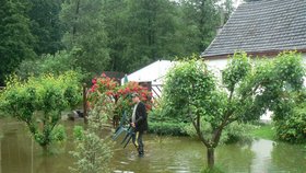 Voda se rozlila z břehů i v Rychnově u Nových Hradů. Petr Malovec zachraňuje zahradní nábytek.
