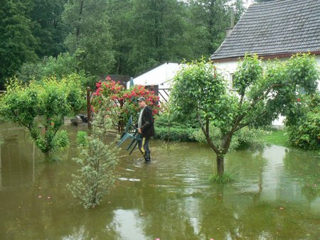 Voda se rozlila z břehů i v Rychnově u Nových Hradů. Petr Malovec zachraňuje zahradní nábytek.
